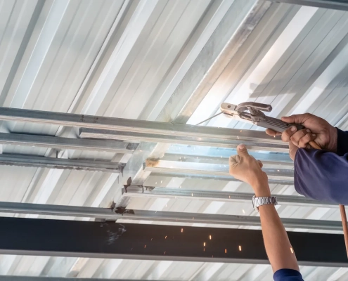 installation de portes de garages asap fermetures 1500 Soudage de structures métalliques avec une pince.