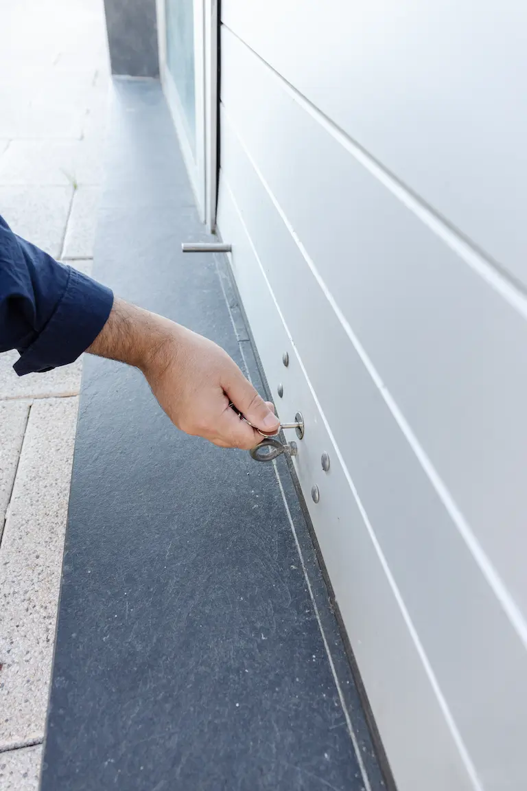installation de portes de garages asap fermetures (2) (1) Main insérant clé dans serrure de porte.