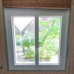 Vue jardin depuis fenêtre intérieure.