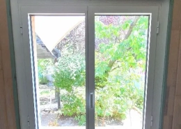 Vue jardin depuis fenêtre intérieure.