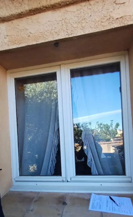 Fenêtre avec rideaux blancs et document sur rebord.