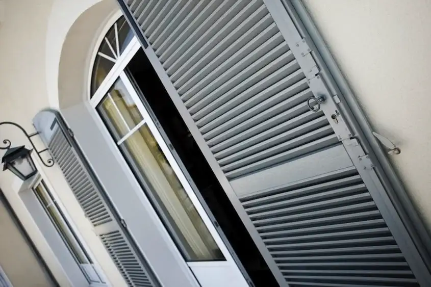 Volets gris et porte-fenêtre ouverte.