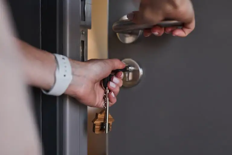 gros plan serrure porte entree vue sur des mains de femme qui ferme une porte à clé