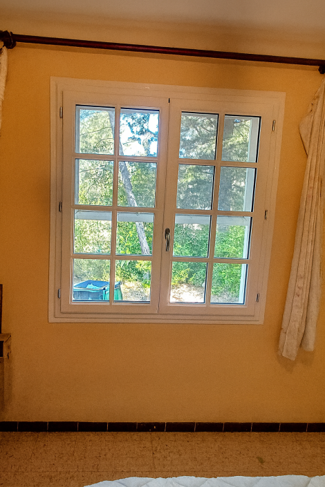 Fenêtre avec vue sur jardin verdoyant.