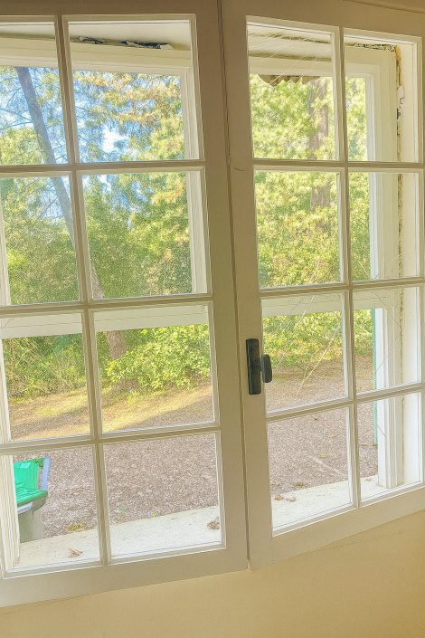 Vue extérieure depuis une fenêtre ouverte en bois.