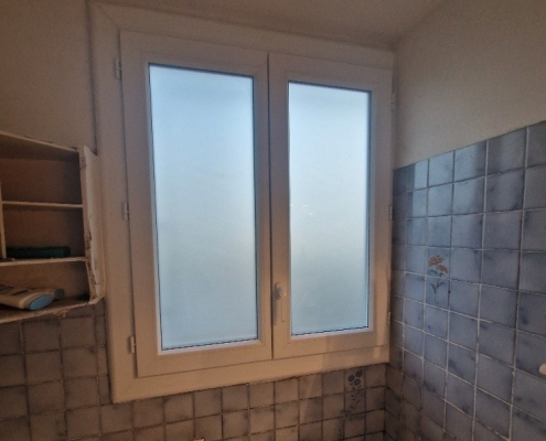 Fenêtre de salle de bain avec carrelage bleu.