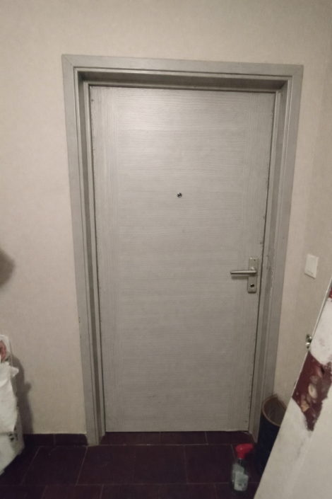 Porte d'entrée grise avec judas et poignée.