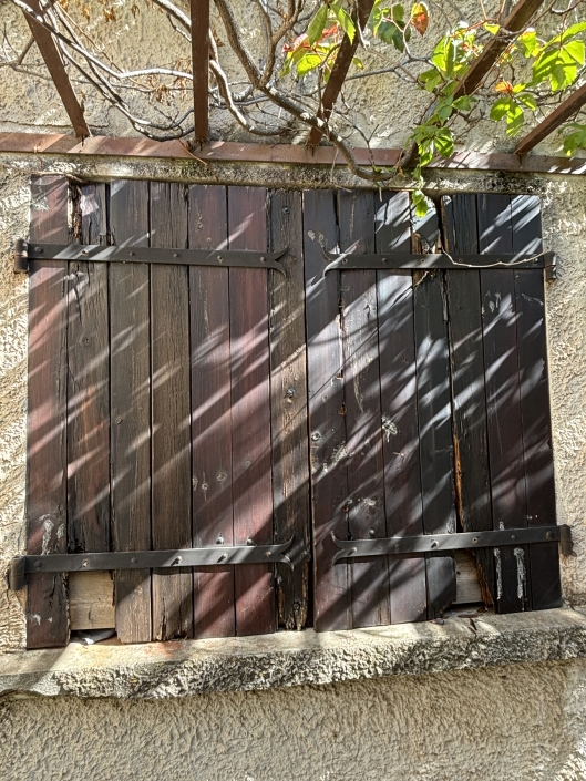 Volets en bois avec lierre sur le mur.