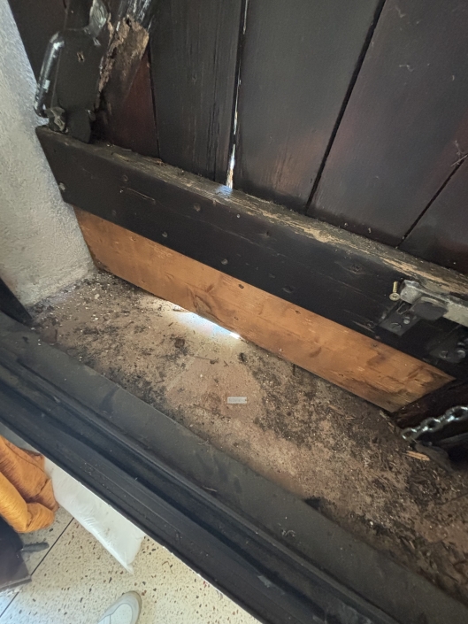 Bas de porte en bois abîmé et éclairé.